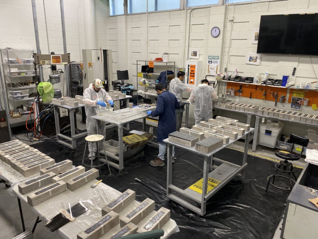 Technicians preparing concrete beam specimens in accredited laboratory
