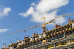 A modern construction site with cranes against a clear blue sky, showcasing urban development.